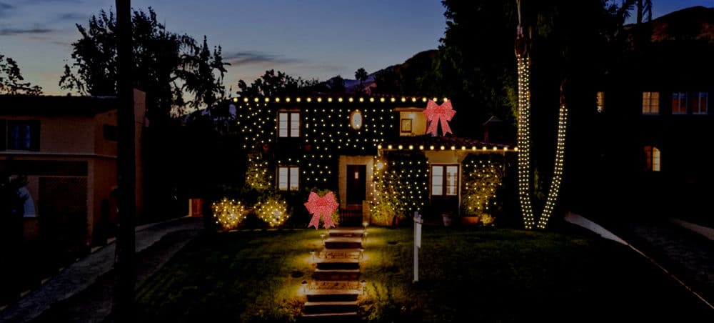 Festively decorated house with bright lights and bows for the holiday season at night.